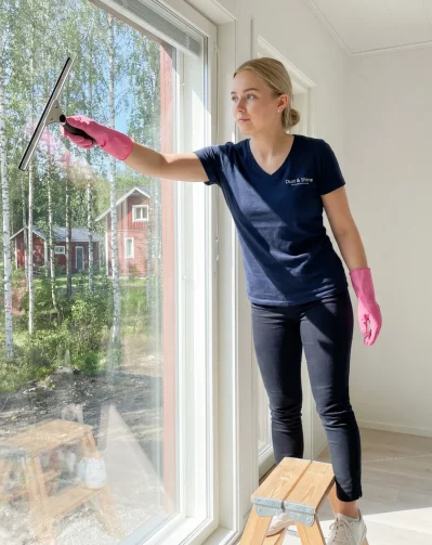 Ikkunanpesu Espoo – Dust & Shine siivooja pesee suurta olohuoneen ikkunaa lastalla